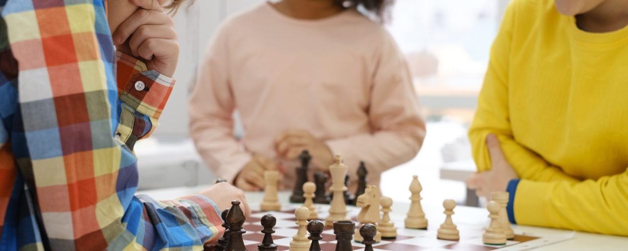 multiethnic-kids-playing-chess-board-game-at-school-e1650351500800.jpg